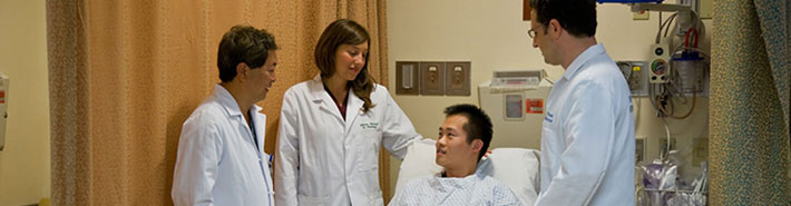  doctors consulting Asian patient in bed